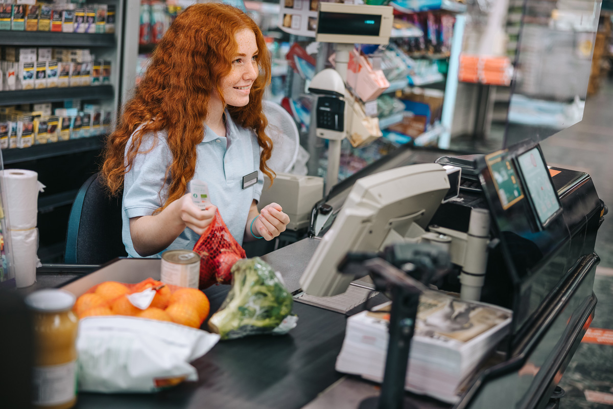 A supermarket cashier scanning items at checkout while assisting a customer, ensuring a fast and seamless shopping experience.